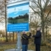 Wethouder Jan Menninga en Eltje Pijper onthullen met het bouwbord de start van de aanleg van het nieuwe kunstgrasveld