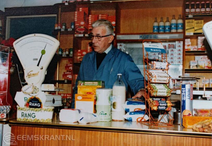 Foto: HV Loppersum: Kruidenier Geut in zijn winkel aan de Nieuwstraat in Loppersum, 1980. –