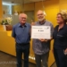 Wiebe Zijlstra (gastheer) en Albertha Jagersma (gastvrouw) overhandigen de cheque aan Arie Schuur (midden) van de Stichting Noaberschap Appingedam.
