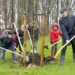 Foto: Wethouder Boersma van de Gemeente Midden Groningen plant de eerste boom samen met een aantal leerlingen