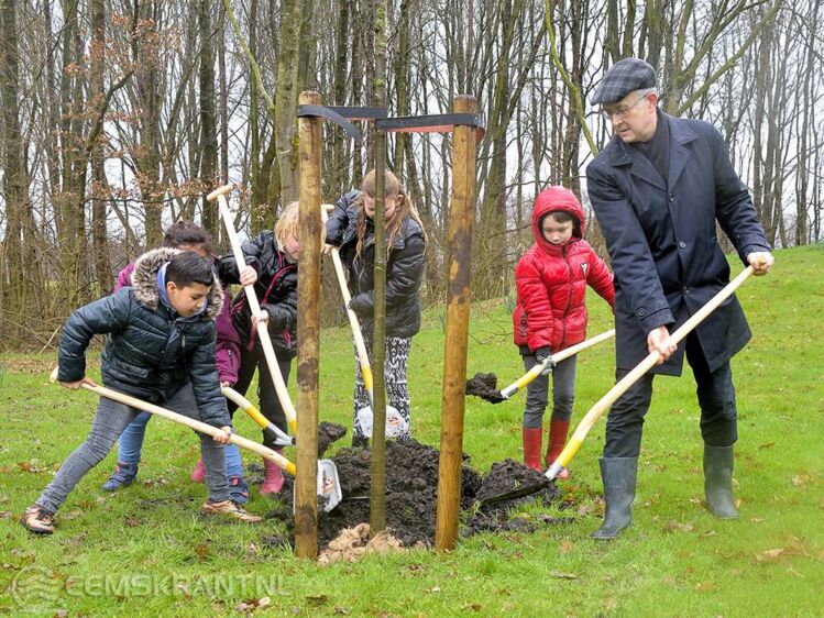 Foto: Wethouder Boersma van de Gemeente Midden Groningen plant de eerste boom samen met een aantal leerlingen