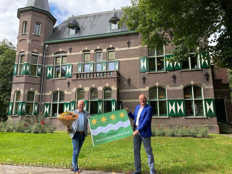 Emme Groot, bestuursvoorzitter van Economic Board Groningen, feliciteert wethouder Harmannus Blok van gemeente Het Hogeland met de benoeming ‘Het mooiste dorp van Nederland’. Hiervoor overhandigt hij een speciale Winsumer vlag met opdruk.