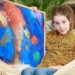 Annika (12) toont trots haar schilderij ‘Op weg naar de ruimte’ .Foto: Stichting Kunst & Cultuur