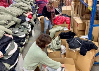 Vrijwilligers van Maxima sorteren de jassen voor de vestigingen.