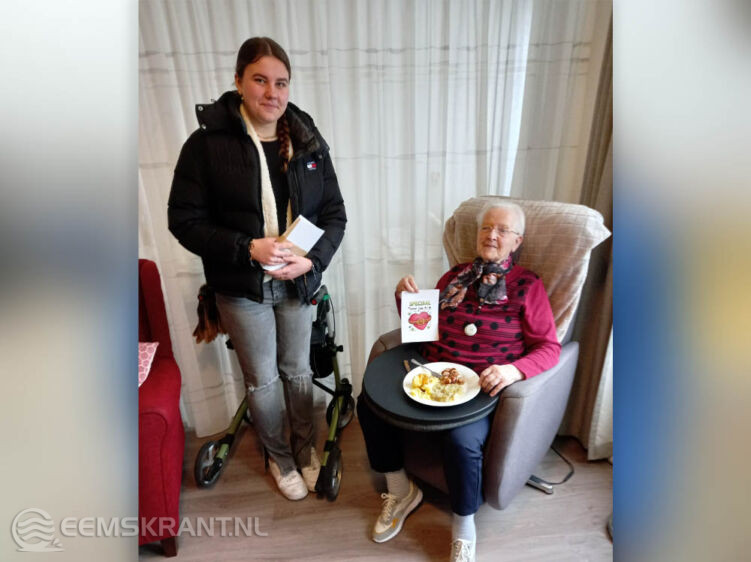 Bente Musch, leerling van Campus VO Eemsdelta, geeft aan mevrouw Stoit-Baar, bewoner van Damsterheerd, haar kaart.