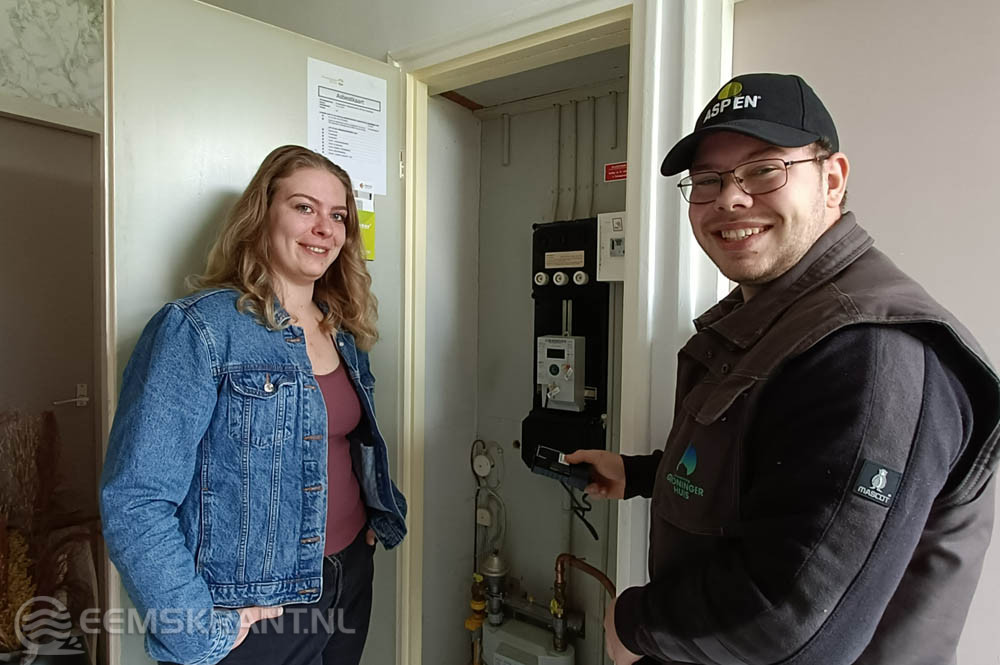 Medewerker van woningstichting Groninger Huis installeert een energiedisplay bij een huurder