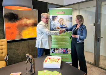 Kristel de Visser (Buurtgezinnen) overhandigt het jubileumboek aan wethouder Evert Offereins.