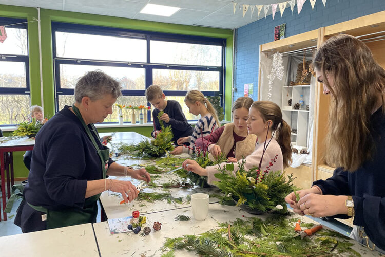 Basisschoolleerlingen maken kerststukjes in het bloemschiklokaal van DCTerra